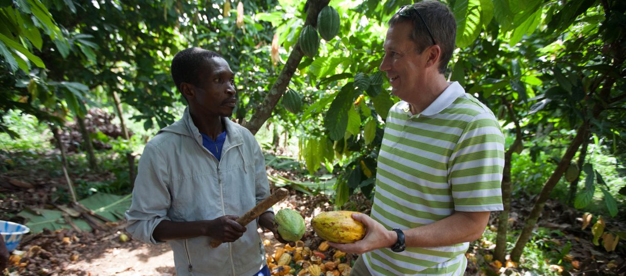 CEO of Endangered Species Chocolate, Curt Vander Meer stands with cocoa farmer in Cote d'Ivoire holding freshly harvest cocoa pods.