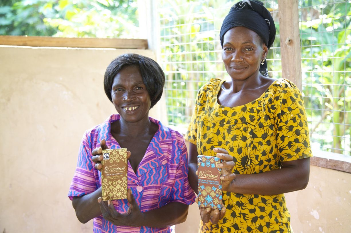 Two women cocoa farmers holding Divine chocolate bars.