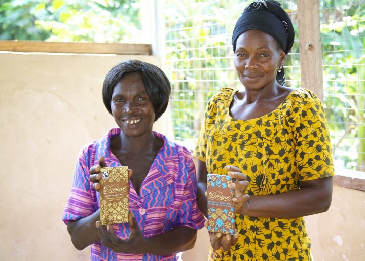 Two women cocoa farmers holding Divine chocolate bars.