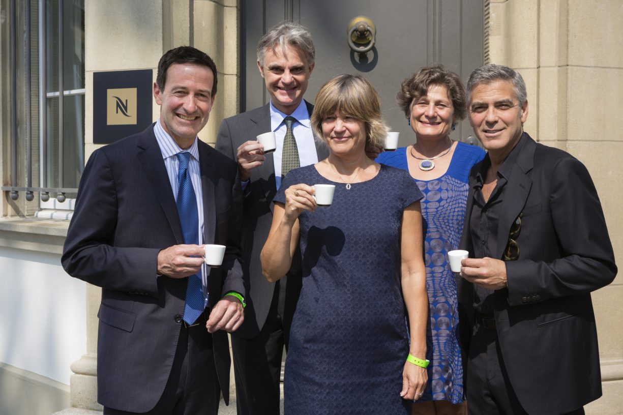 George Clooney holding espresso along with fair trade leaders at the Nespresso Launch event.