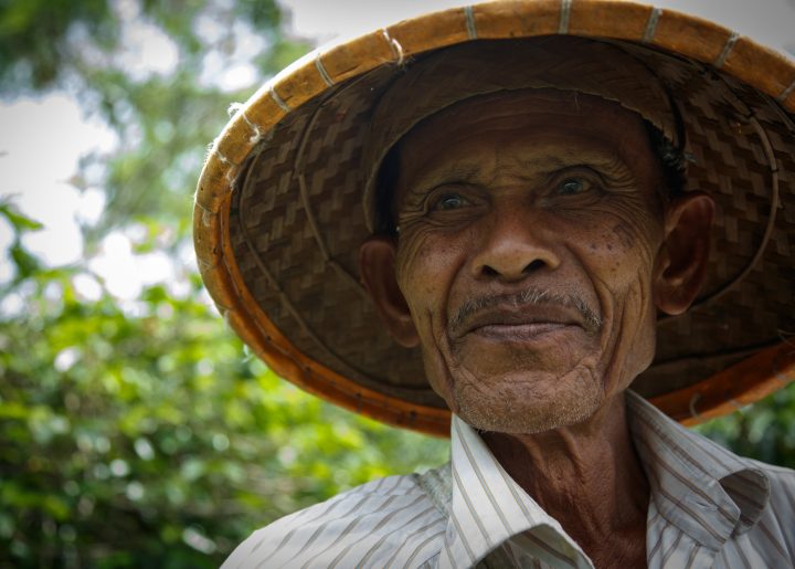 Coffee farmer in broad brimmed hat on his property in Indonesia.