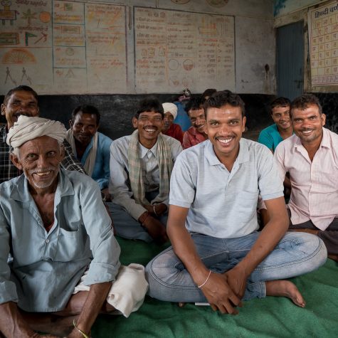Ten men sit in a room to discuss changes in their Fairtrade cotton cooperative.