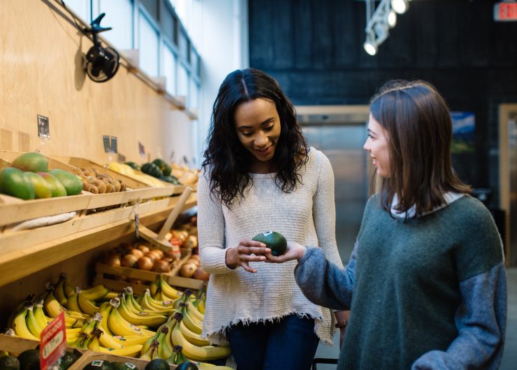 Two women look at Fairtrade certified produce in an organic market.