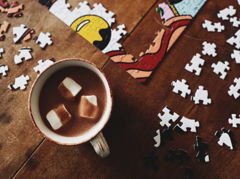 Fairtrade certified hot cocoa in a cozy mug with marshmallows and a puzzle in mid-creation.