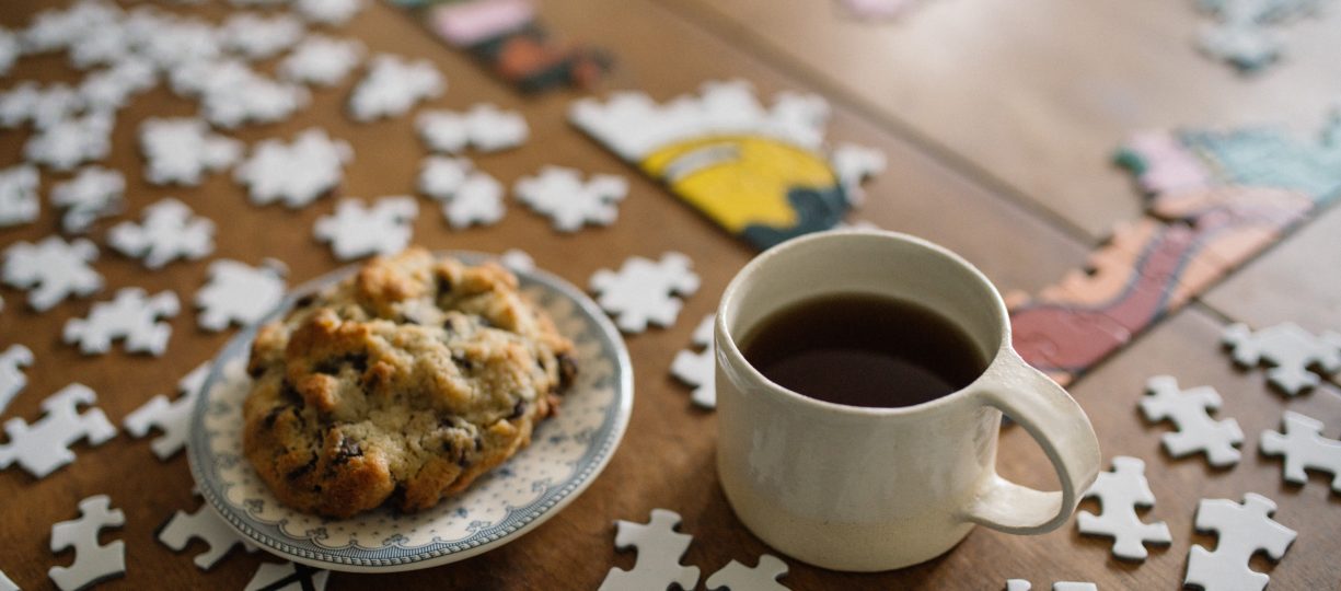 Fairtrade certified coffee sits next to a delicious cookie and a puzzle.
