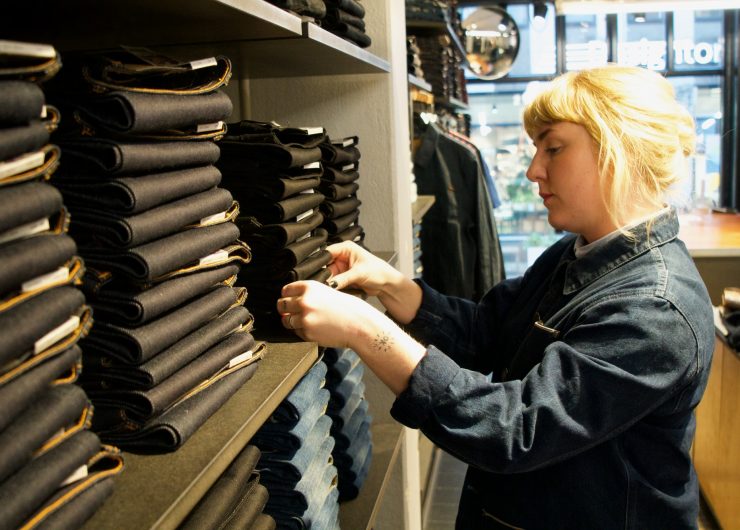 Store worker at Nudie Jeans organizes a stack of denim.