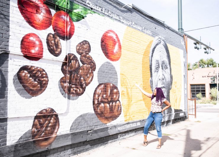 Influencer, Anne Marie John visiting Fairtrade America's mural in Denver, CO at Kaladi coffee roasters highlighting a Fairtrade coffee farmer.