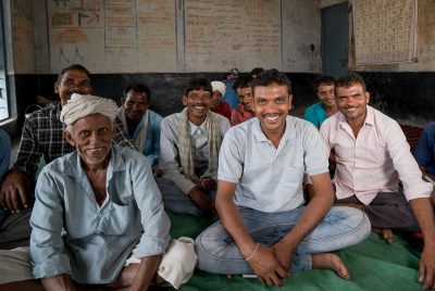 Ten men sit in a room to discuss changes in their Fairtrade cotton cooperative.