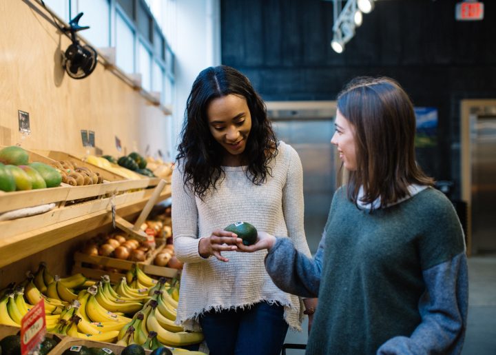 Two women look at Fairtrade certified produce in an organic market.