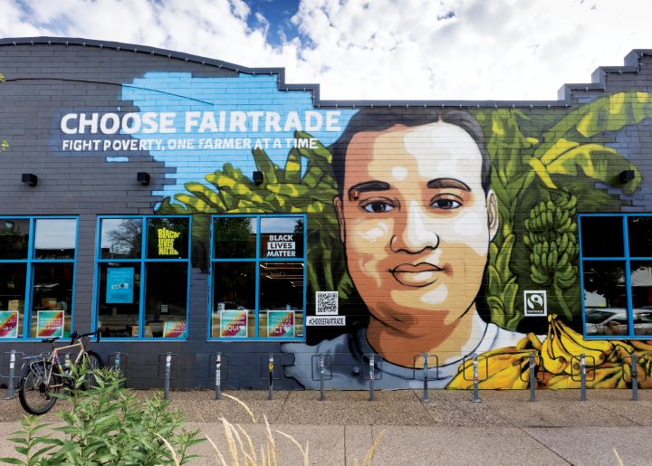 Vibrant Minneapolis mural by Reggie LeFlore featuring Fairtrade banana farmer, Johnny, along with bananas and banana trees.