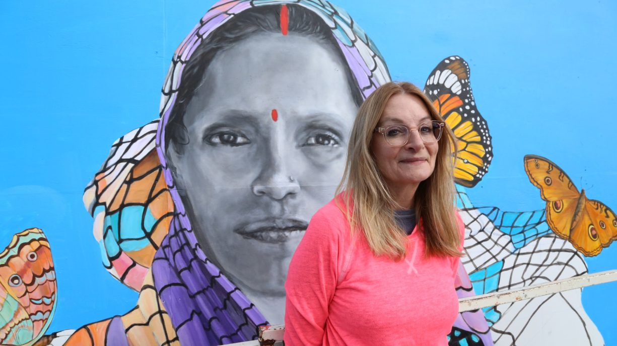 Milwaukee muralist Nova Czarnecki in front of her portrait of farmer Ranjana Maurya at Outpost Natural Foods