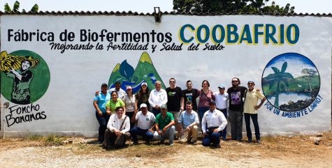 Coobafrio farmers, producers and Fairtrade staff in front of a mural in 2019