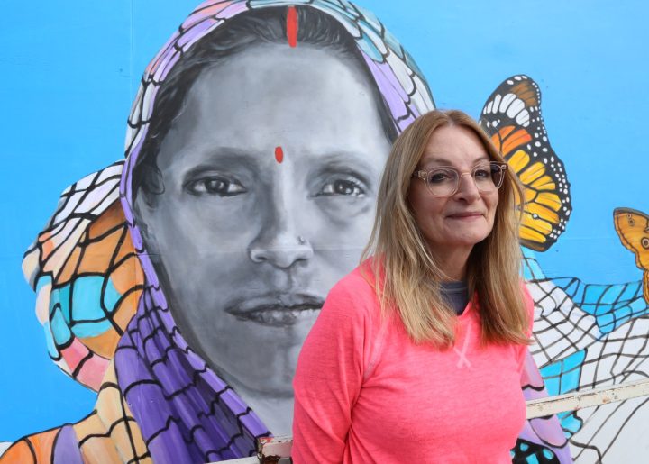 Milwaukee muralist Nova Czarnecki in front of her portrait of farmer Ranjana Maurya at Outpost Natural Foods