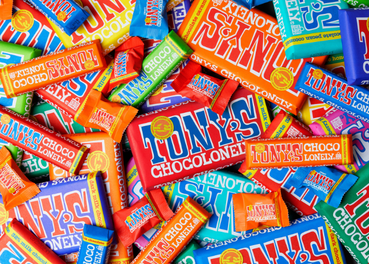 A pile of Tony's Chocolonely's bars with colorfol packaging and varied sizes.