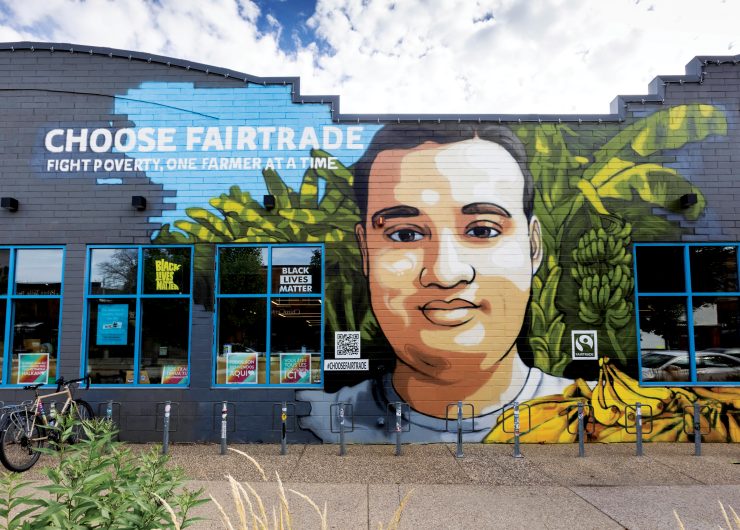 Vibrant Minneapolis mural by Reggie LeFlore featuring Fairtrade banana farmer, Johnny, along with bananas and banana trees.