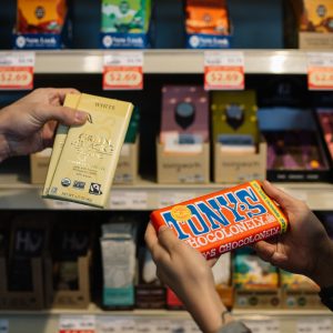 Shoppers holding Fairtrade certified chocolate bars from Tony's Chocolonely and Green & Black.