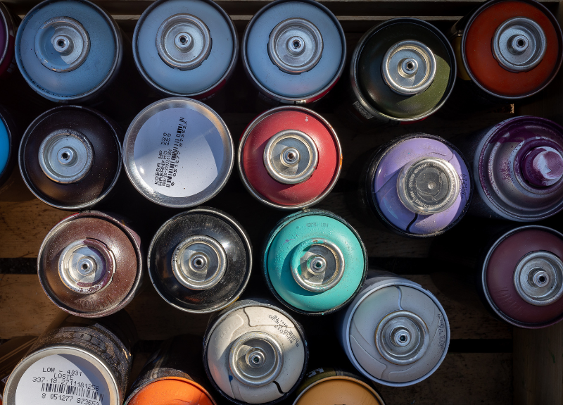 Birds eye view of a collection of spray paint cans of varying colors in a box.